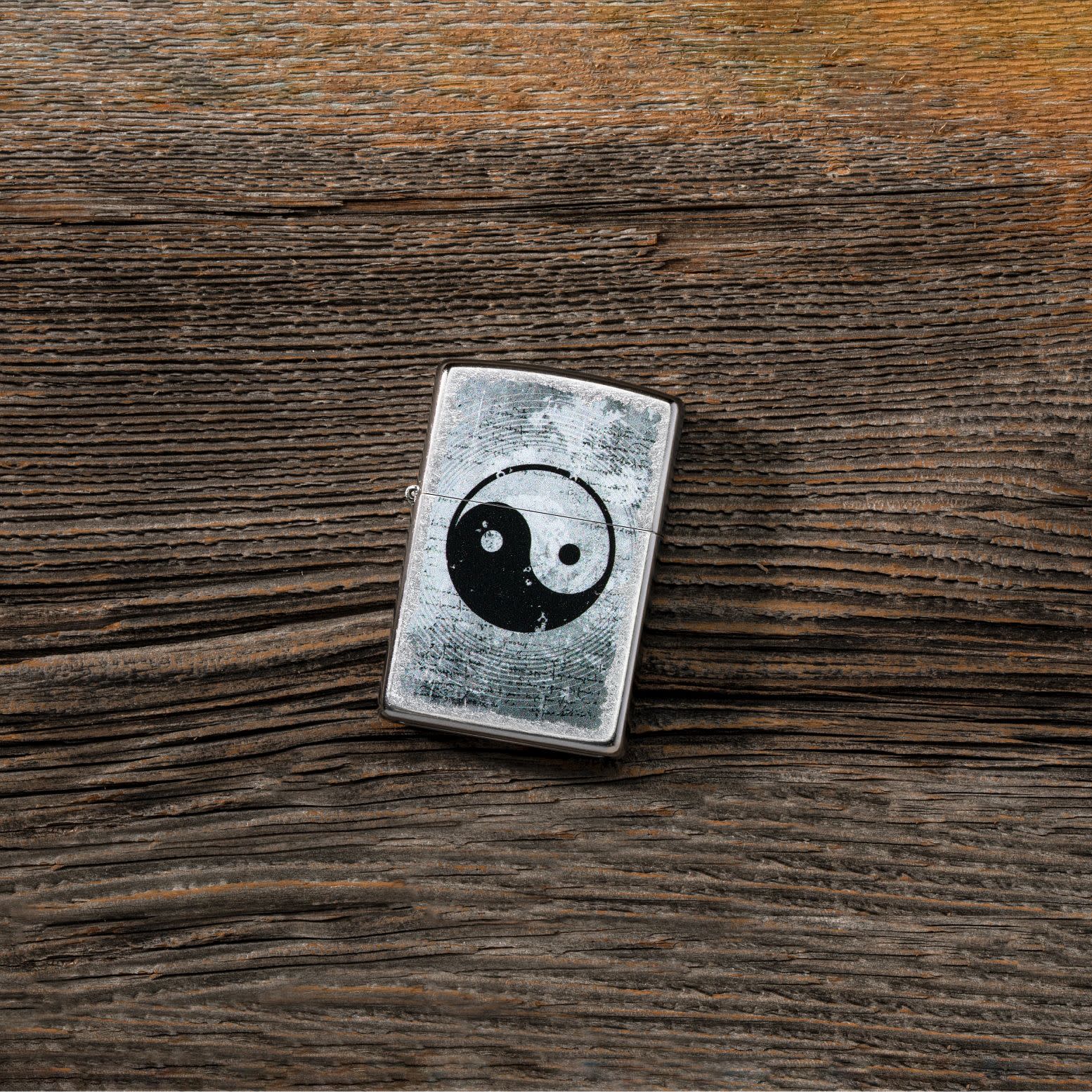 Lifestyle image of Yin Yang Design Street Chrome?äó Windproof Lighter laying on a wooden table. 