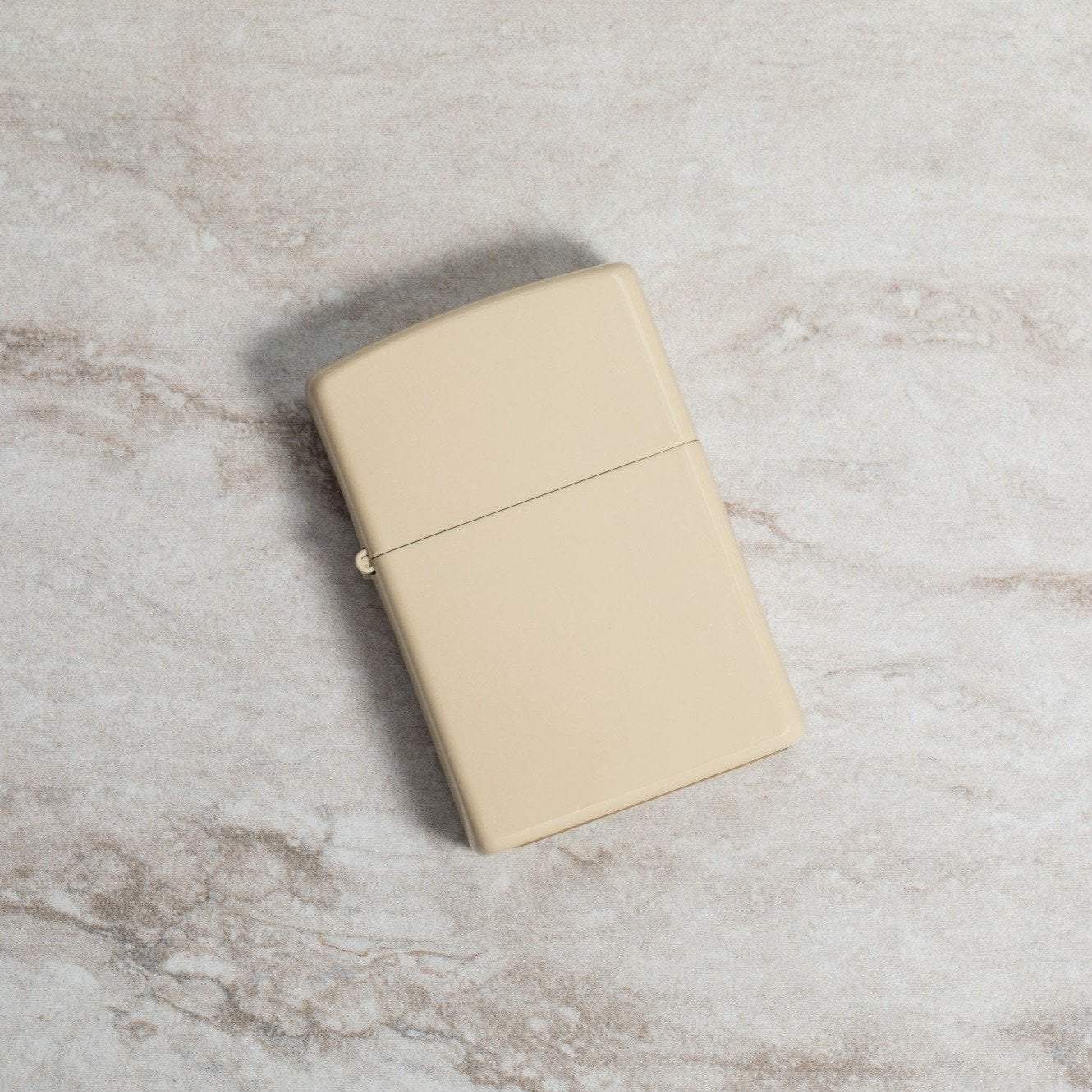 Lifestyle image of Classic Flat Sand Windproof Lighter laying on a marble surface